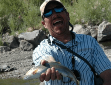Fishing guide smiles while holding trout