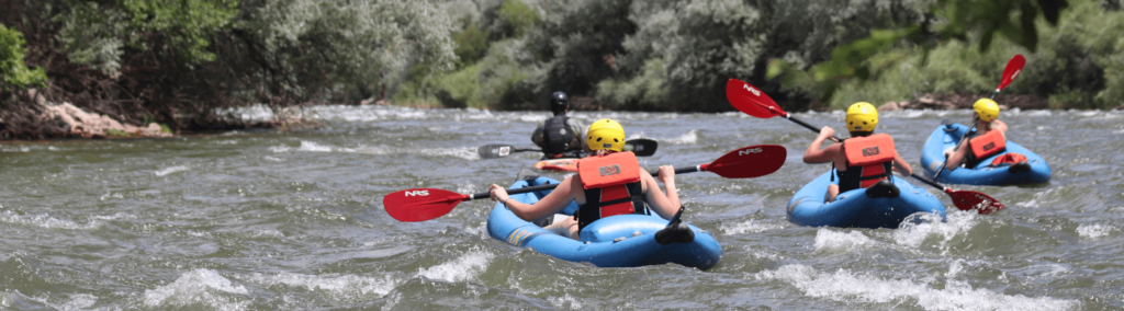 Group of people paddling through the Arkansas River in inflatable kayaks