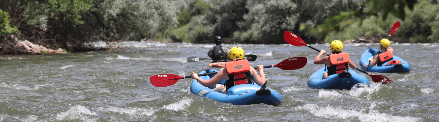 Group of people paddling through the Arkansas River in inflatable kayaks